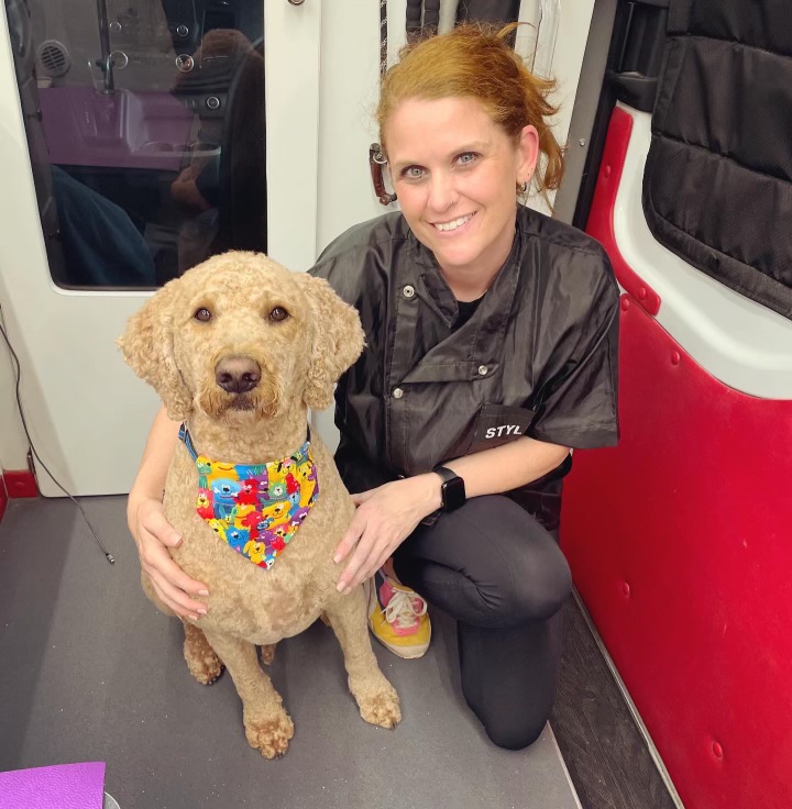 Ashleigh standing by the grooming van with a dog